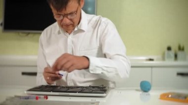 Bir adam dizüstü bilgisayarı tamir ediyor. Bilgisayar tamiri kavramı. Dizüstü bilgisayarı tornavidayla tamir et. Ana kartın donanımının bakımı. Disk tutucu, bilgisayar onarımı