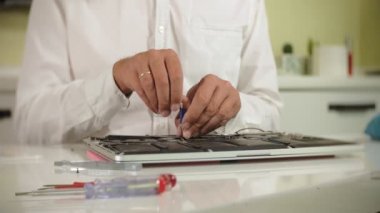 Bir adam dizüstü bilgisayarı tamir ediyor. Bilgisayar tamiri kavramı. Dizüstü bilgisayarı tornavidayla tamir et. Ana kartın donanımının bakımı. Disk tutucu, bilgisayar onarımı