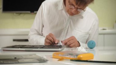 Bir adam dizüstü bilgisayarı tamir ediyor. Bilgisayar tamiri kavramı. Dizüstü bilgisayarı tornavidayla tamir et. Ana kartın donanımının bakımı. Disk tutucu, bilgisayar onarımı