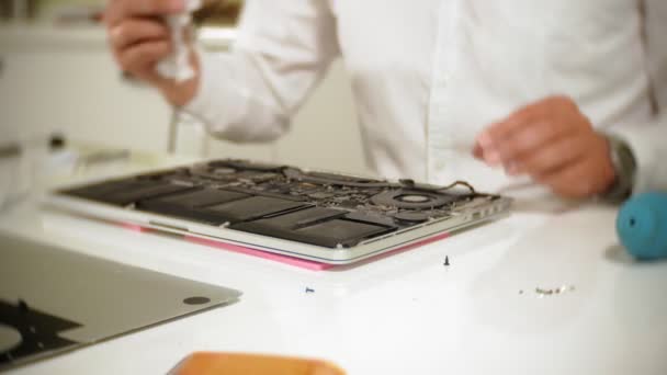 Un hombre está reparando un portátil. El concepto de reparación de computadoras. Primer plano de hombre reparación placa base portátil con un destornillador. Mantenimiento del hardware de la placa base. Soporte de disco, reparación de computadoras — Vídeos de Stock