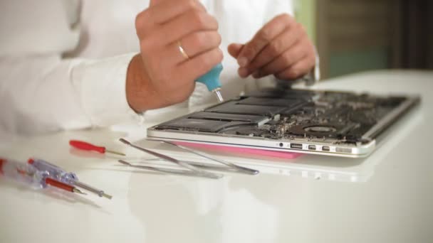 Un hombre está reparando un portátil. El concepto de reparación de computadoras. Primer plano de hombre reparación placa base portátil con un destornillador. Mantenimiento del hardware de la placa base. Soporte de disco, reparación de computadoras — Vídeos de Stock