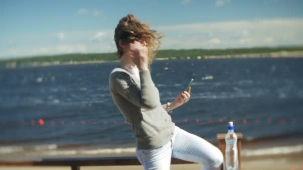 Een vrouw maakt gebruik van een smartphone op het strand van — Stockvideo