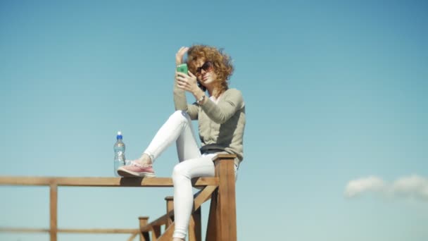 O femeie foloseste un smartphone pe plaja — Videoclip de stoc