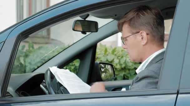 Rijpe zakenman in auto uitgevoerd. Zoeken van documenten — Stockvideo