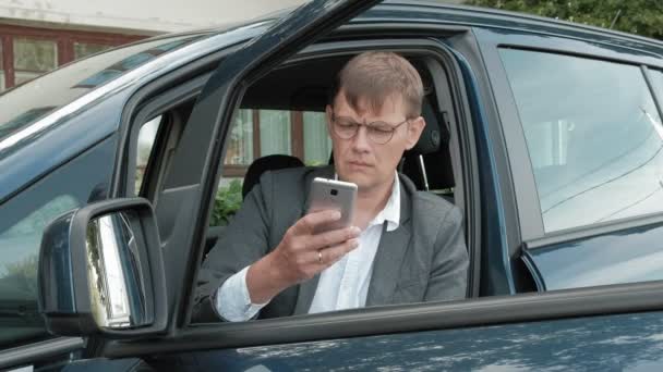 Mature businessman in car uses smartphone — Stock Video