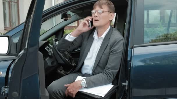 कारमध्ये प्रौढ व्यापारी स्मार्टफोन वापरते — स्टॉक व्हिडिओ