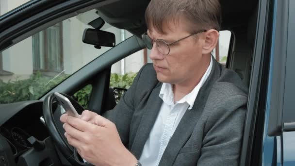 車で成熟したビジネスマンは、スマート フォンを使用してください。 — ストック動画