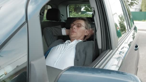 Зрелый бизнесмен в машине лежит на разложившемся переднем сиденье — стоковое видео