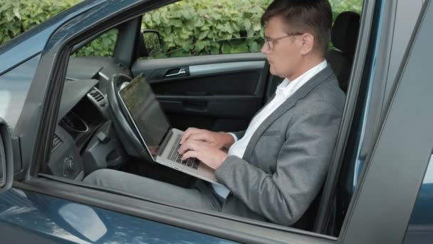 Rijpe zakenman in auto die op laptop werkt — Stockvideo