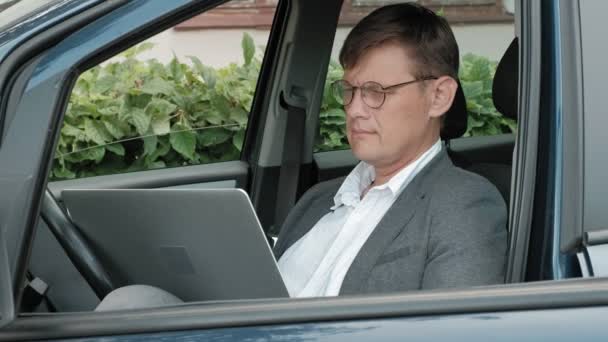 Homme d'affaires mature en voiture travaillant sur ordinateur portable — Video