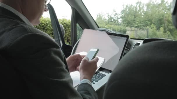 Rijpe zakenman in auto die op laptop werkt — Stockvideo