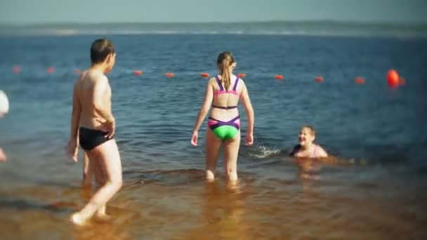 Niños felices están saltando en las olas del mar . — Vídeos de Stock