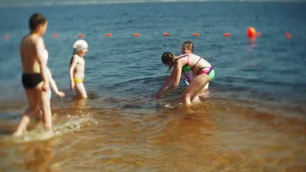 Glada barn hoppar i havet vågor. — Stockvideo