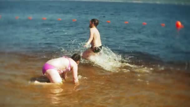 De gelukkige kinderen zijn springen in de golven van de zee. — Stockvideo