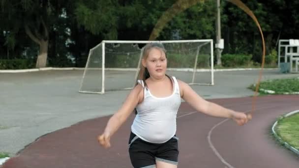 Little fat girl jumping rope in the stadium — Stock Video