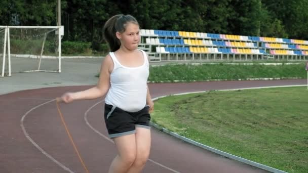 Kis kövér lány jumping kötelet a stadionban — Stock videók