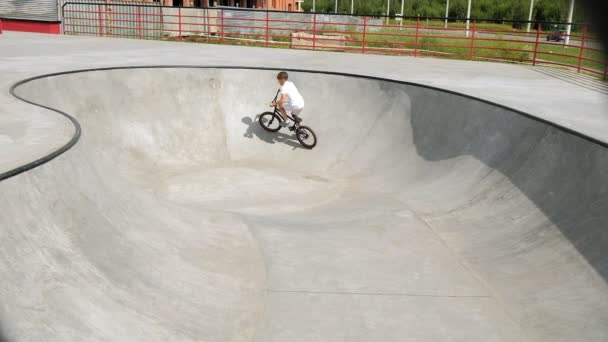 Ein Junge reitet an einem sonnigen Tag in einem Skateboard-Park seine Tricks mit dem Fahrrad. Superzeitlupe — Stockvideo