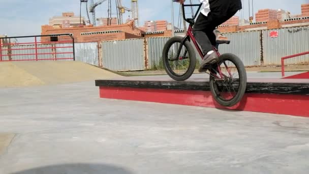 Um menino está montando BMX truques de ciclismo em um parque de skate em um dia ensolarado. Movimento super lento — Vídeo de Stock