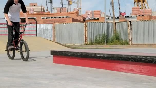 Um menino está montando BMX truques de ciclismo em um parque de skate em um dia ensolarado. Movimento super lento — Vídeo de Stock