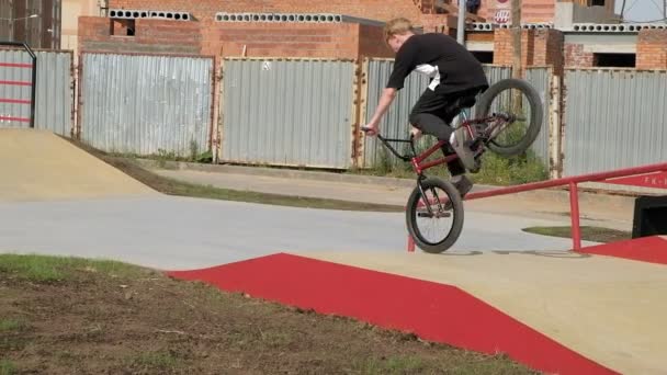 Мальчик ездит на велосипеде BMX трюки в скейтборд-парке в солнечный день. Super Slow Motion — стоковое видео