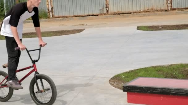 Un ragazzo sta cavalcando BMX ciclismo trucchi in un parco skateboard in una giornata di sole. Super rallentatore — Video Stock