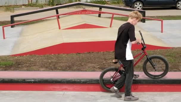 Ein Junge reitet an einem sonnigen Tag in einem Skateboard-Park seine Tricks mit dem Fahrrad. Superzeitlupe — Stockvideo