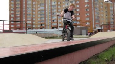 Bir çocuk Bmx Bisiklet hileler kaykay parkı güneşli bir günde biniyor. Çok yavaş hareket