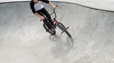 Bir çocuk Bmx Bisiklet hileler kaykay parkı güneşli bir günde biniyor. Çok yavaş hareket