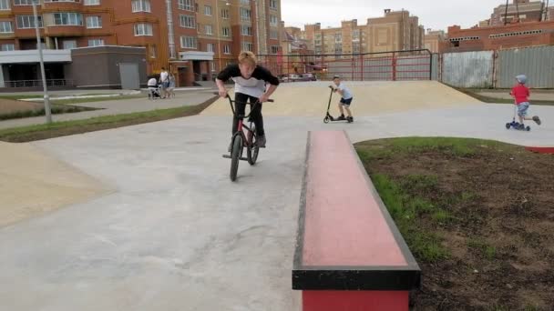 Хлопчик їхав Bmx їзда на велосипеді трюки на скейтборді парку на сонячний день. Супер-повільний рух — стокове відео