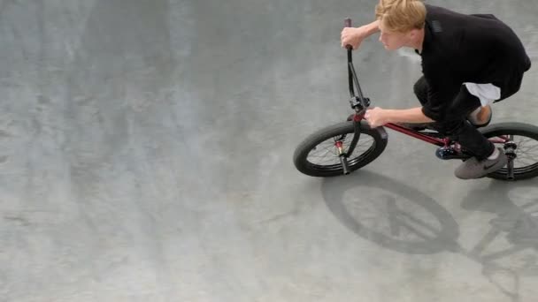 Chłopiec jest jazda na rowerze Bmx tricks w park deskorolka w słoneczny dzień. Super Slow Motion — Wideo stockowe