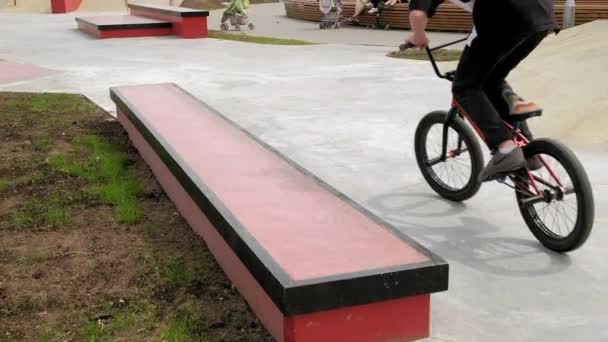 Un niño está montando trucos de ciclismo BMX en un parque de skate en un día soleado. Super cámara lenta — Vídeo de stock