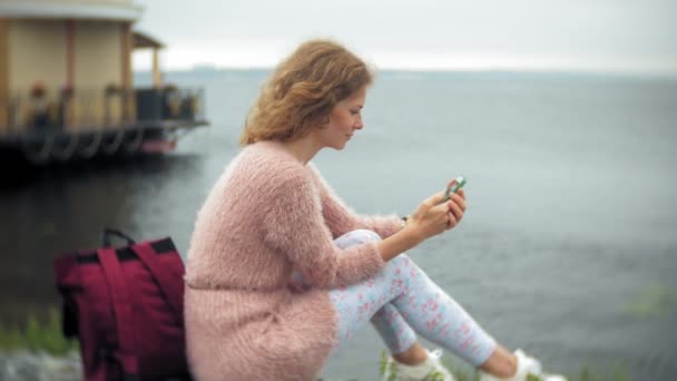 Девушка с помощью смартфона на берегу моря, яхта и парусный спорт в гавани . — стоковое видео
