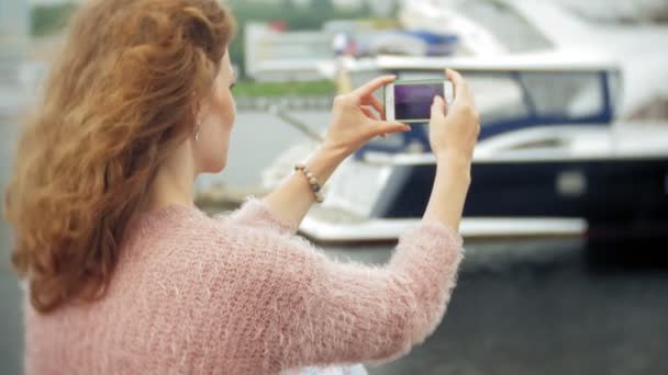 Ei jente som bruker smarttelefon ved sjøen, yacht og seiler i havnen . – stockvideo