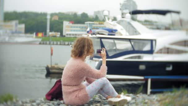 Девушка с помощью смартфона на берегу моря, яхта и парусный спорт в гавани . — стоковое видео