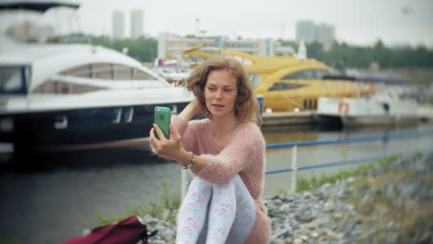 Una chica usando un teléfono inteligente en la playa, yate y vela en el puerto . — Vídeos de Stock