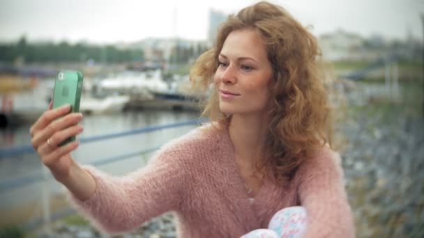 Una chica usando un teléfono inteligente en la playa, yate y vela en el puerto . — Vídeos de Stock