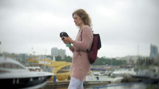 Une fille utilisant un smartphone au bord de la mer, yacht et voile dans le port . — Video