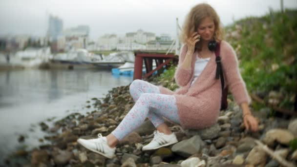 Seorang gadis menggunakan smartphone di tepi laut, kapal pesiar dan berlayar di pelabuhan . — Stok Video