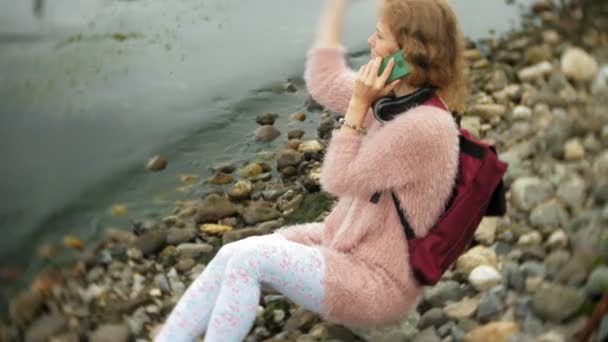 Una chica usando un teléfono inteligente en la playa, yate y vela en el puerto . — Vídeos de Stock