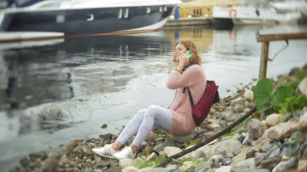 En flicka med en smartphone på seaside, yacht och segling i hamnen. — Stockvideo