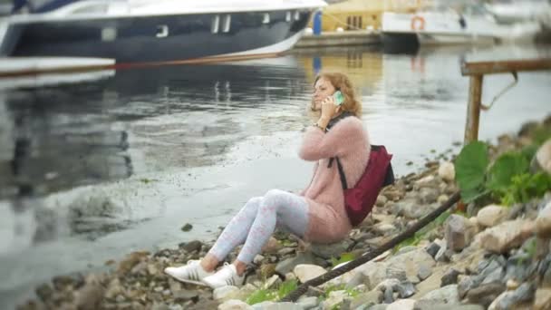 Una chica usando un teléfono inteligente en la playa, yate y vela en el puerto . — Vídeos de Stock