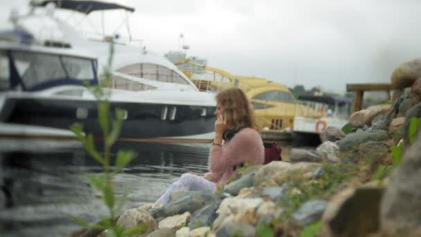 Una chica usando un teléfono inteligente en la playa, yate y vela en el puerto . — Vídeo de stock