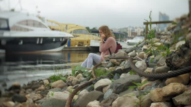 Dívka pomocí smartphone v přímořské, jachty a plachetnice v přístavu. — Stock video