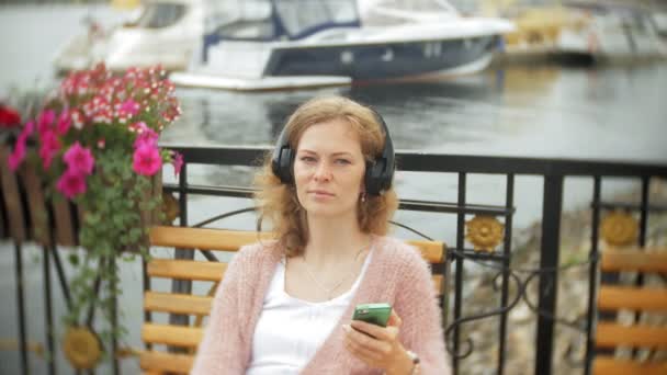 Girl Using Smartphone Bench Flower Beach Listening Music Headphones Dancing — Stock Video