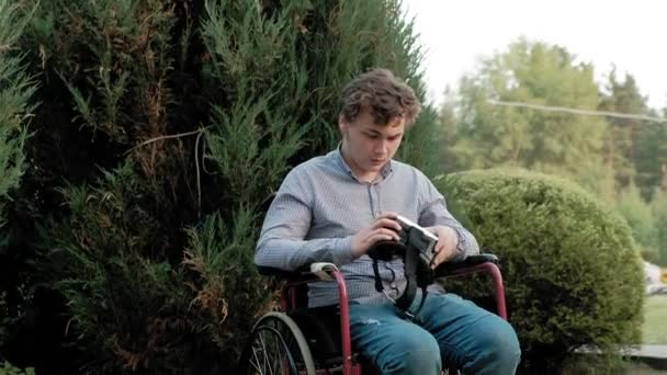 Een gehandicapte man in een rolstoel stoel jurken een vr-helm — Stockvideo