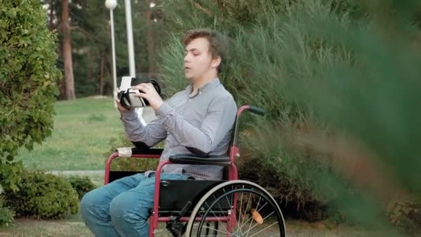 Un hombre discapacitado en silla de ruedas viste un casco de realidad virtual — Vídeos de Stock