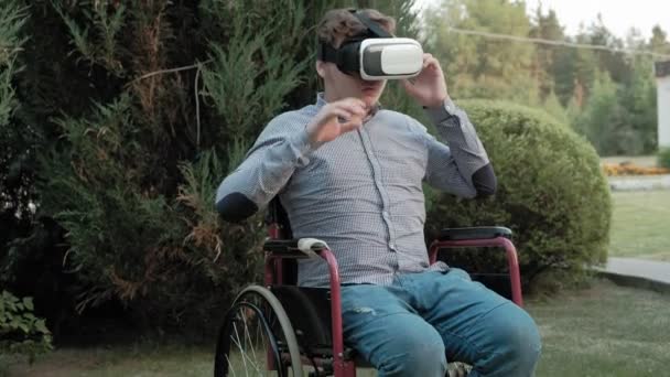 Un hombre discapacitado en silla de ruedas viste un casco de realidad virtual — Vídeos de Stock