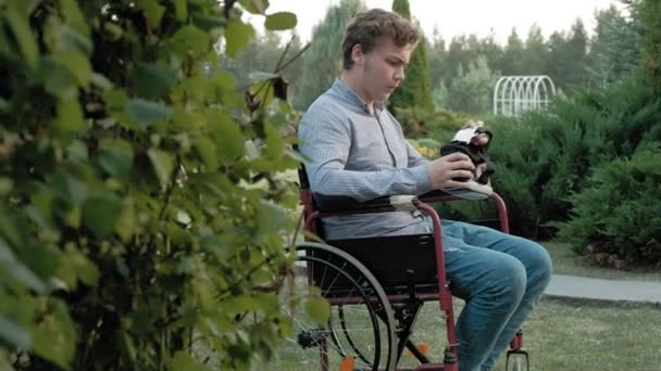 Um homem com deficiência em uma cadeira de rodas veste um capacete de realidade virtual — Vídeo de Stock