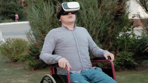 Un hombre discapacitado en silla de ruedas utiliza un casco de realidad virtual — Vídeos de Stock