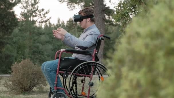Bir tekerlekli sandalye Engelli bir erkekte bir sanal gerçeklik kask kullanır — Stok video